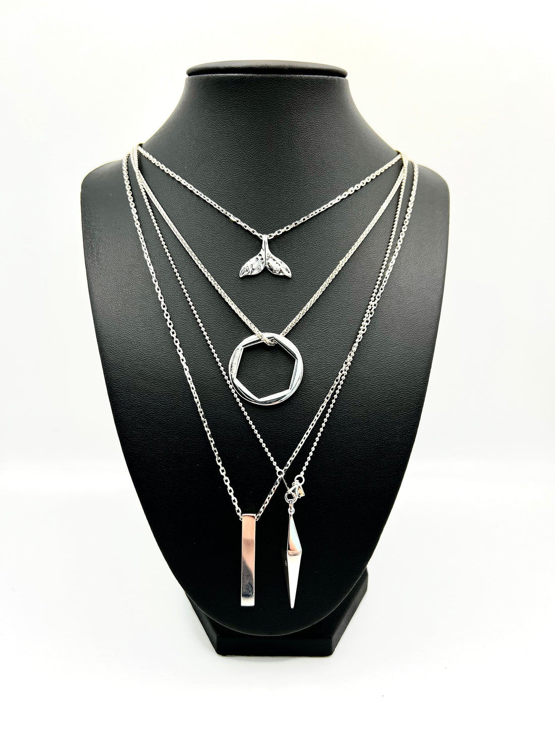 MRVP & Co range of platinum silver necklaces displayed on a black mannequin bust, featuring a selection of distinctive pendants.