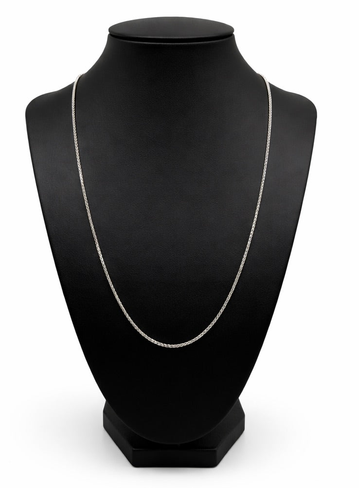 Silver necklace on a black mannequin bust against a white background